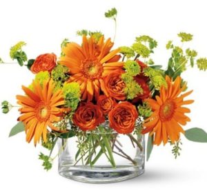 orange daisies and roses with green accents in vase