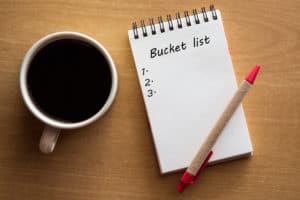 Coffee, white notebook, red pen, bucket list