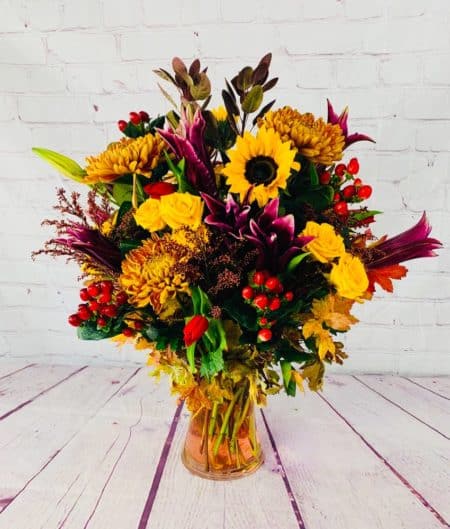 Deep reds, yellows, and oranges are sure to warm up your night! Sunflowers, lilies, roses, and alstromeria fill this gathering vase. Perfect for any occasion.